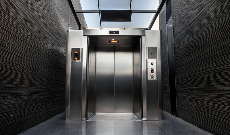 Elevador com portas e batentes em aço inox no hall de um prédio
